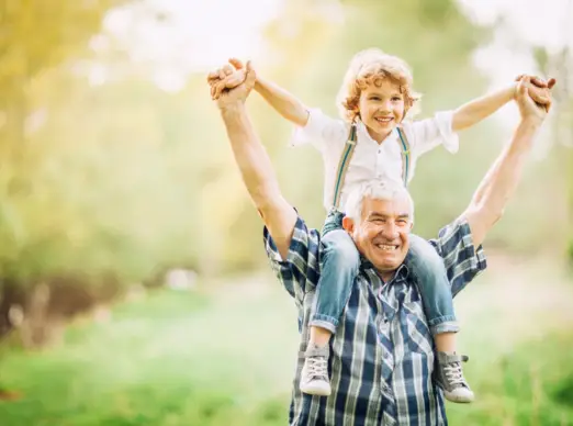 image of a grandfather carrying his grandson on his shoulders.